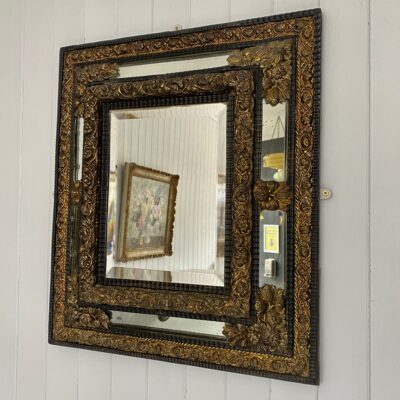 A Continental Repousse Cushion Framed Brass and Ebonised MIrror
